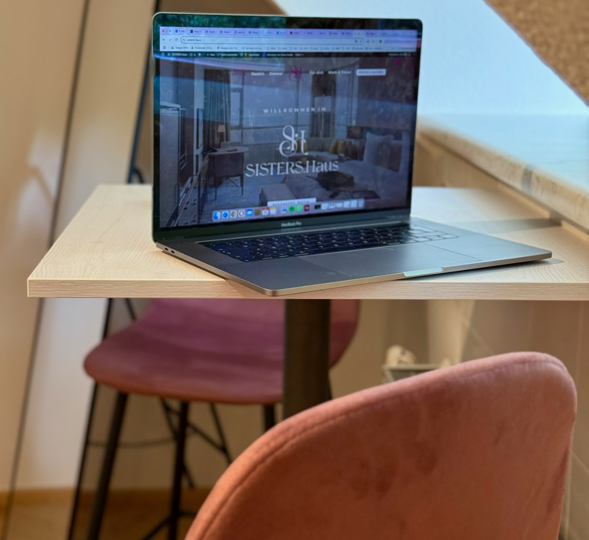 Work & Travel Angebot Symbolbild Zimmer, Schreibtisch mit Laptop und Koffer